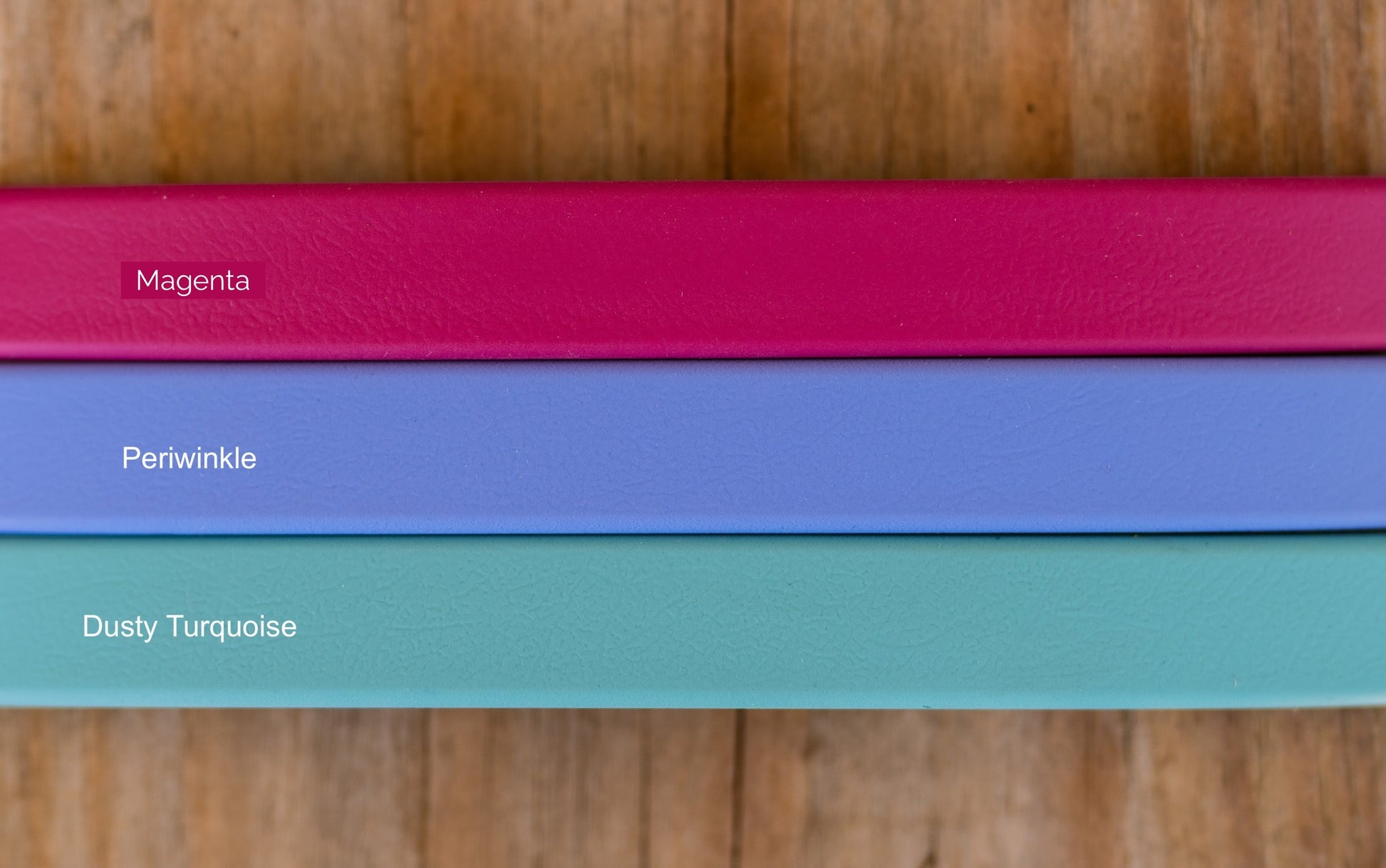 Three horizontal color swatches labeled 'Magenta', 'Periwinkle', and 'Dusty Turquoise' on a wooden background.